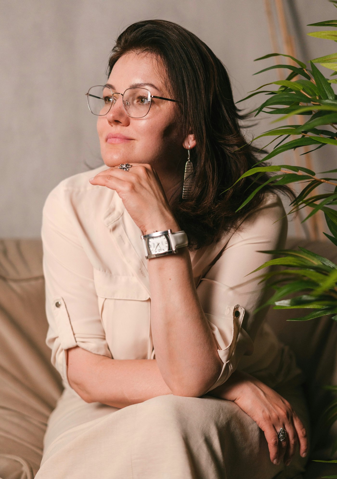 Helena Moraes, psicóloga, sentada num sofá claro ao lado de uma planta